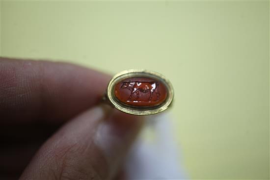 An antique yellow metal and oval carnelian cabochon ring carved with a standing bull, the shank with decorative pierced shoulders